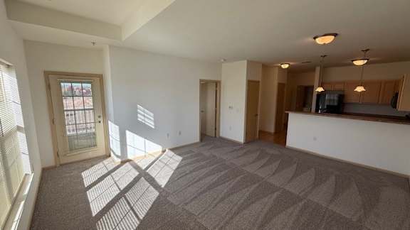 A spacious room with a carpeted floor and a large window letting in natural light.