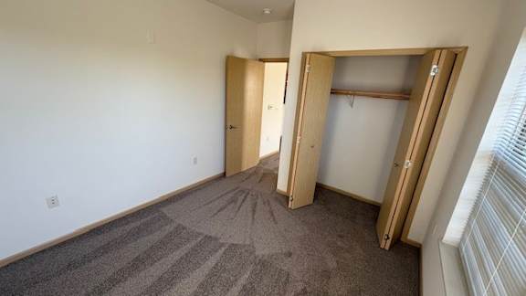A room with carpeted floor and two open doors.