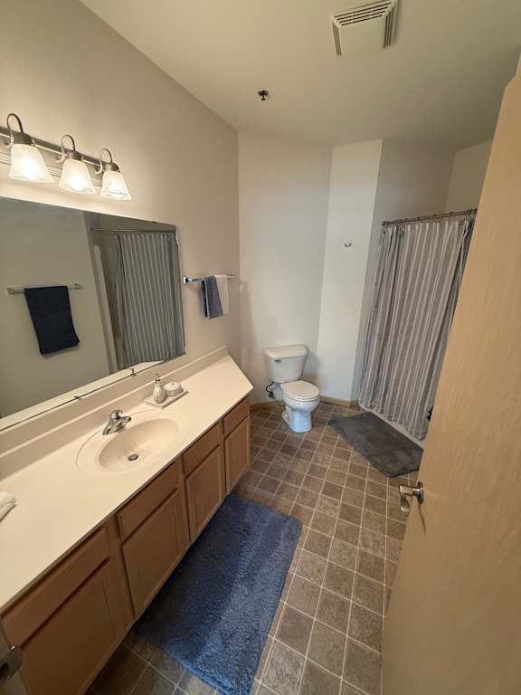 A bathroom with a sink, mirror, toilet and shower.