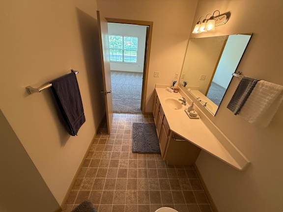 A bathroom with a sink, mirror, and towel rack.