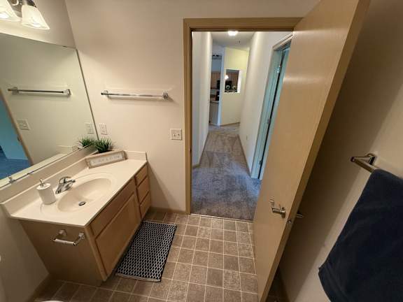 A bathroom with a sink, mirror, and towel rack.