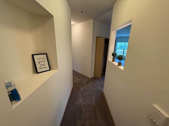 A hallway with a framed sign that says "It's so good to be home."