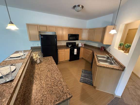 A kitchen with a black refrigerator and black stove.
