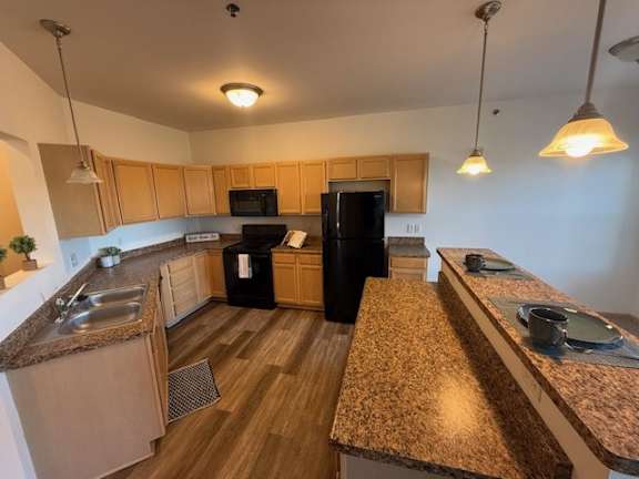A kitchen with a black fridge and wooden cabinets.