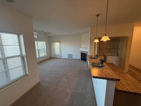 A spacious living room with a kitchen area in the background.