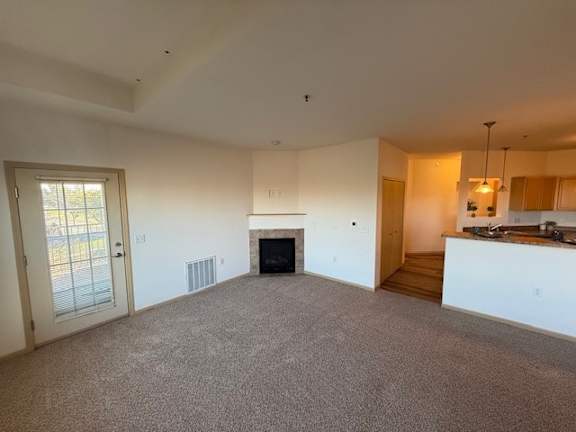 A large, empty room with a fireplace and a carpeted floor.