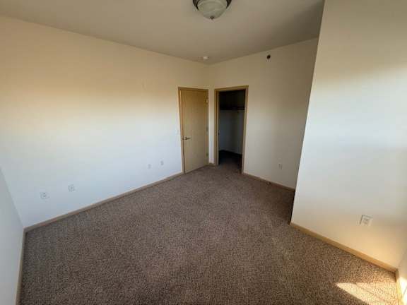 A carpeted room with a doorway leading to another room.