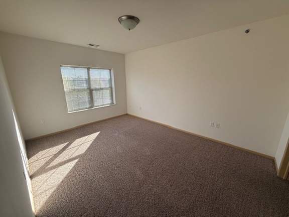 A room with a carpeted floor and a window letting in sunlight.