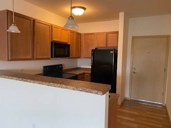 A kitchen with wooden cabinets and a black refrigerator.