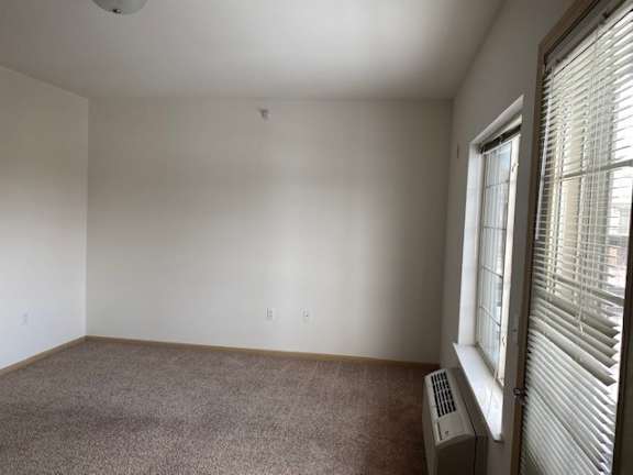 A room with a window and a carpeted floor.