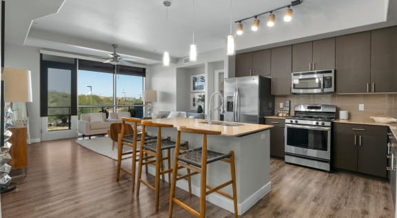 an open kitchen and living room with an island and chairs