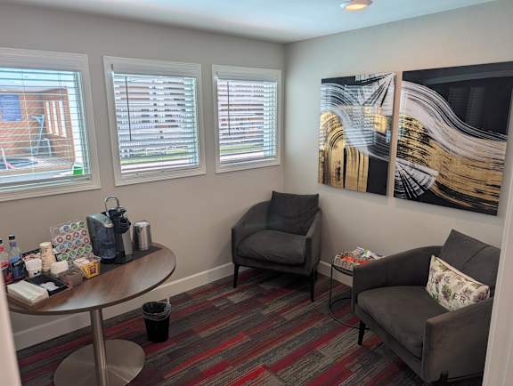 A room with a table, chairs, and a painting on the wall.