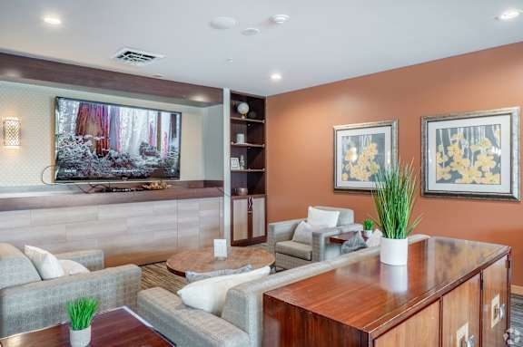 A living room with a grey couch, a wooden table, and a painting on the wall.