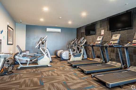 A gym with treadmills, elliptical machines, and other exercise equipment.