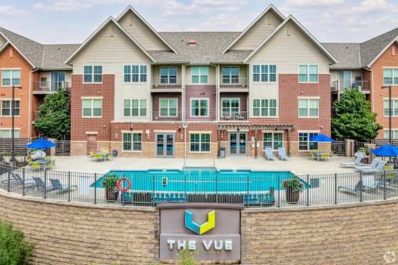 A large brick building with a pool in front and a sign that says "The Vue".