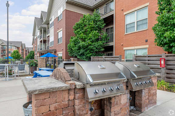A brick BBQ grill is in front of apartment buildings.