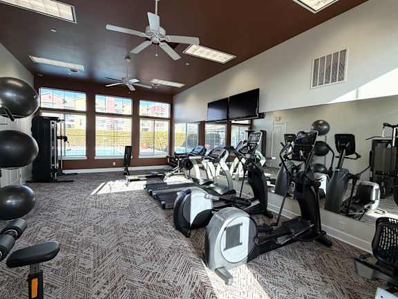 A gym with a variety of equipment including treadmills, stationary bikes, and weight machines.