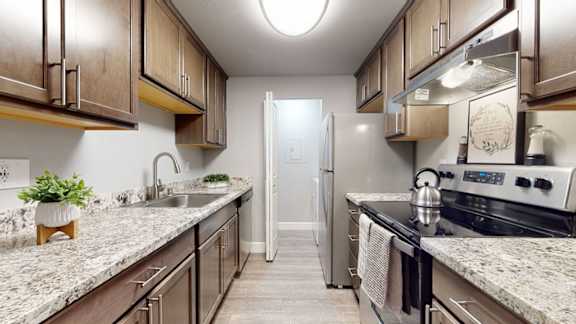 A kitchen with brown cabinets and a marble countertop.