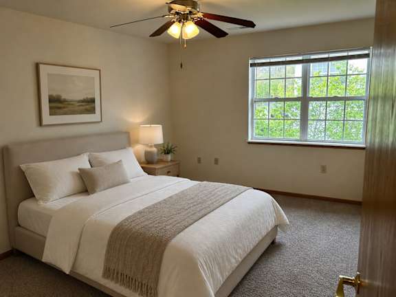 A bedroom with a large bed and a ceiling fan.