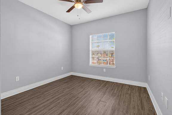 A room with a ceiling fan and a window with blinds.