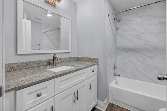 A bathroom with a marble countertop and white fixtures.