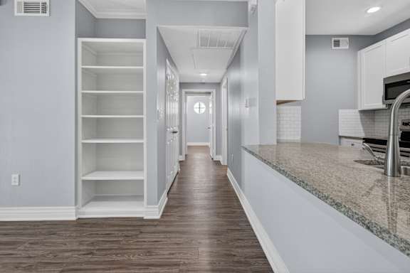 A long hallway with a door at the end and a kitchen area on the right.