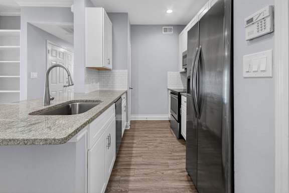 A modern kitchen with a stainless steel refrigerator and a marble countertop.