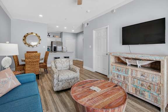 A living room with a blue couch, a wooden coffee table, and a television.