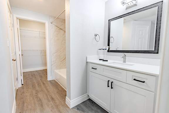 A bathroom with a white vanity and a mirror.
