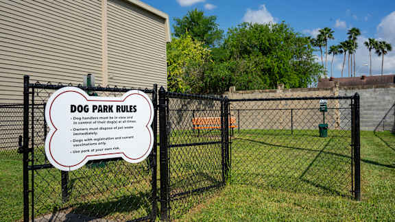 a dog park rules sign on a fence in front of a house