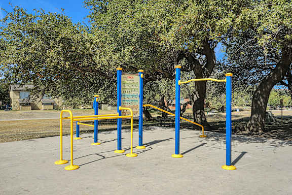 A blue and yellow outdoor gym equipment set up in a park.