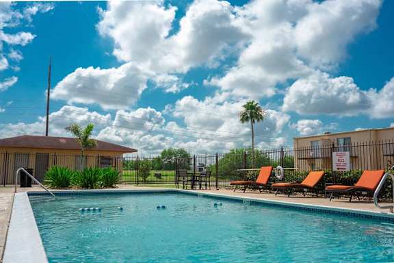 a swimming pool with orange chairs next to a building