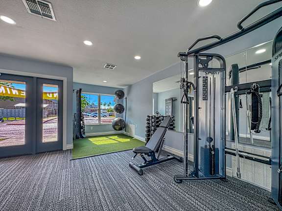 A gym with a variety of equipment including a squat rack and a bench.