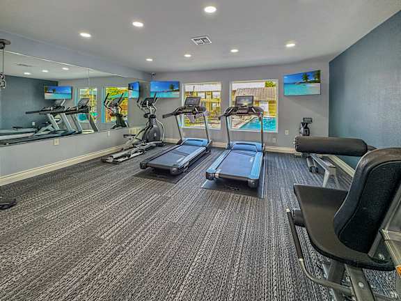 A gym with treadmills, exercise bikes, and a television.