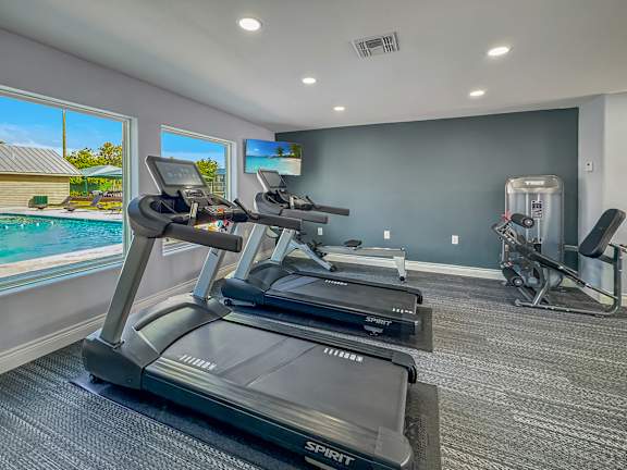 A Spin bike is in a room with a view of a pool and a house.