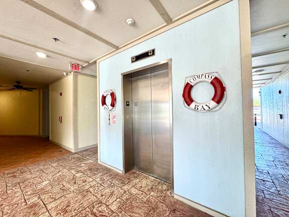 A hallway with a sign that says "EXIT" and a life preserver on the wall.