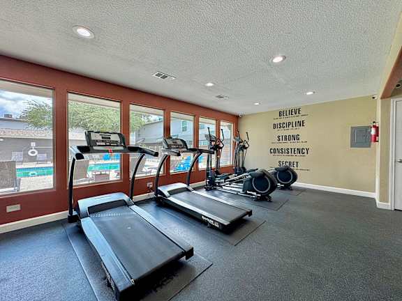 A gym with treadmills and a wall with the words "Believe Discipline Strong Consistency Secret" written on it.