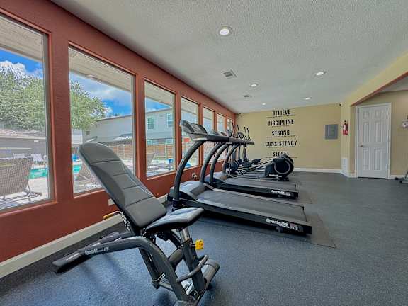 A gym with a row of treadmills and a motivational wall slogan.