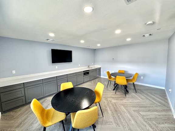 A modern dining room with a black table and yellow chairs.