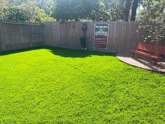 a backyard with a green lawn and a red bench