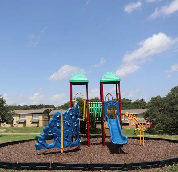 A playground with a blue slide and a climbing structure.