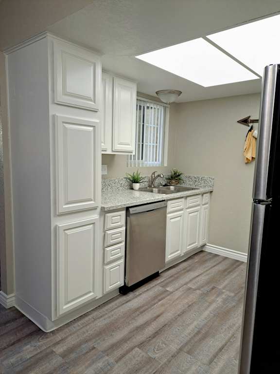 A kitchen with white cabinets and a stainless steel refrigerator at Raintree Apartments, Highland, CA, 92346