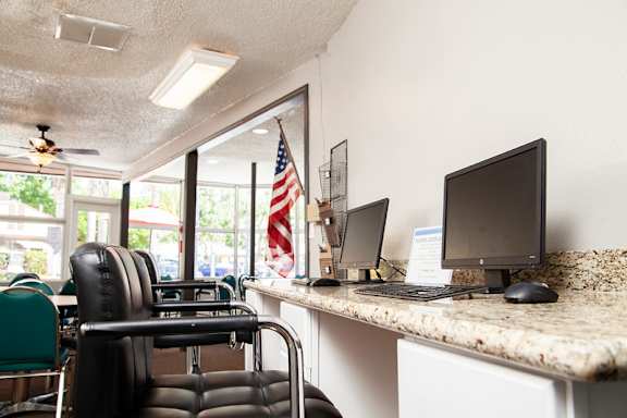 A black leather chair is in front of a desk with two computer monitors at Country Village Apartments, Jurupa Valley, CA, 91752