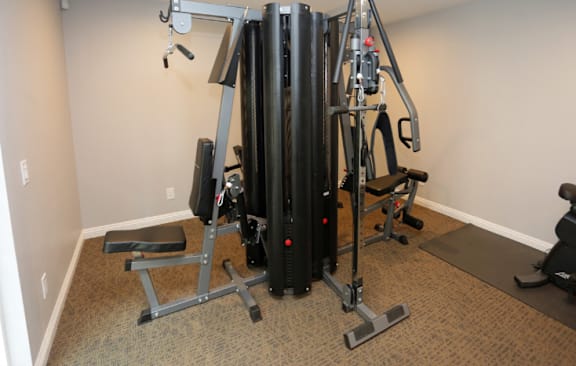 A black and grey home gym setup with a bench and weights  at Bella Park Apartments, California, 92376