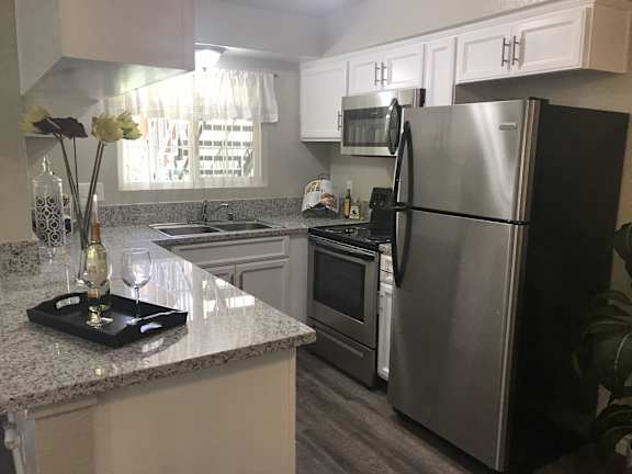 A kitchen with a granite counter top and stainless steel appliances  at Bella Park Apartments, California