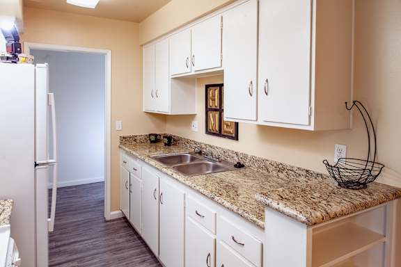 A kitchen with white cabinets and a granite countertop.