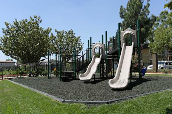 A playground with a slide and climbing structure  at Bella Park Apartments, California