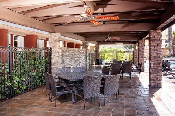 A patio with a table and chairs under a roof at Country Village Apartments, Jurupa Valley, CA
