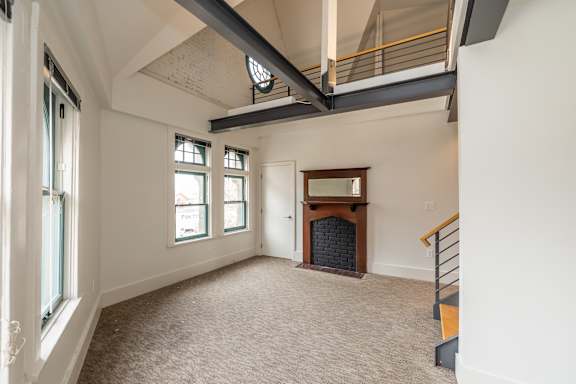 an empty living room with a fireplace and a loft above it