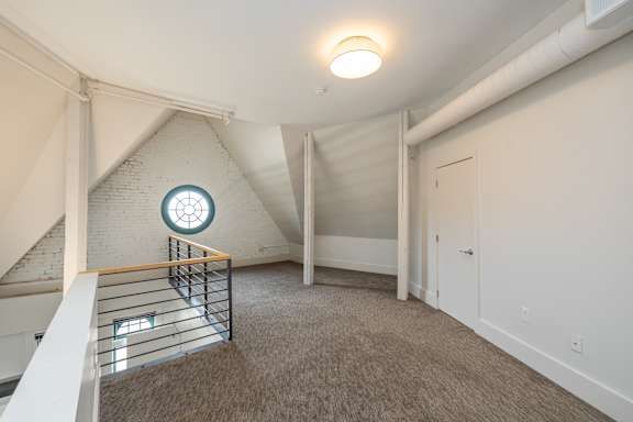 an attic with a window and a staircase with a carpeted floor